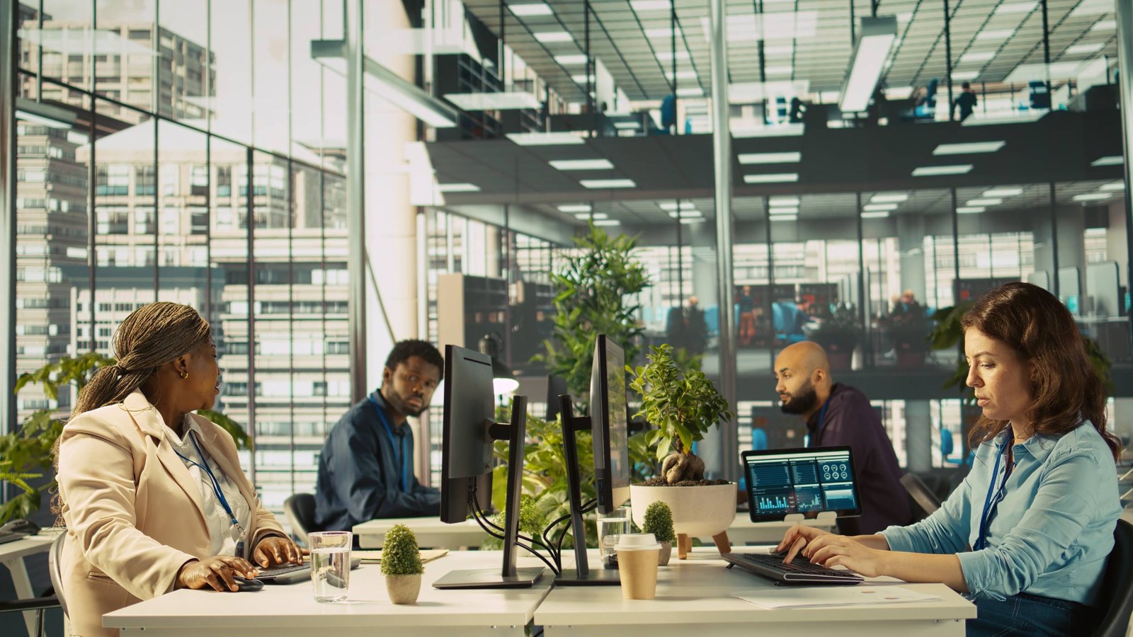 Employees working at desks with monitors in a bright open-plan office